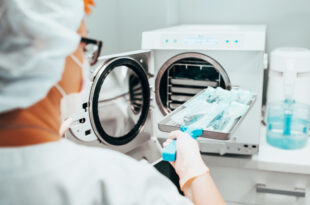 Sterilisation medizinischer Instrumente - eine Krankenschwester lädt ein Tablett mit Instrumenten zur Desinfektion in einen Autoklaven.